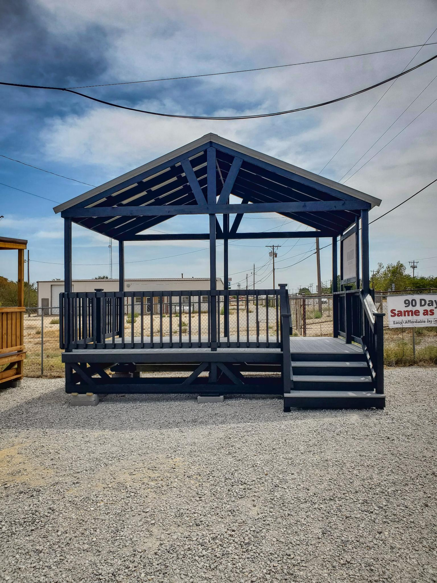 Black stained covered deck with gable metal roof and stairs